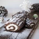 The side view of a chocolate yule log showing the cream filling and dusting of powdered sugar falling like snow
