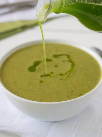 Drizzling basil oil on top of the soup