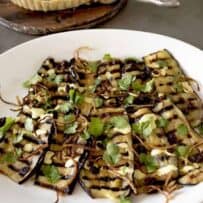 Sliced grilled aubergine/eggplant on a large white plate.
